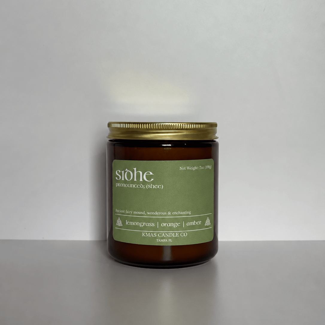 Sidhe | Wooden Wick Candle - KMAS Candle Co-Candles-KMAS Candle Co-A candle in an amber glass jar with a gold metal lid and a muted green label. The label reads 'siohe' and 'KING GULACHCO'.